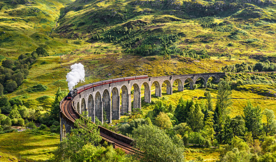 Glenfinnan Railway Viaduct in Scotland with the Jacobite steam train passing over (photo via miroslav_1 / iStock / Getty Images Plus(