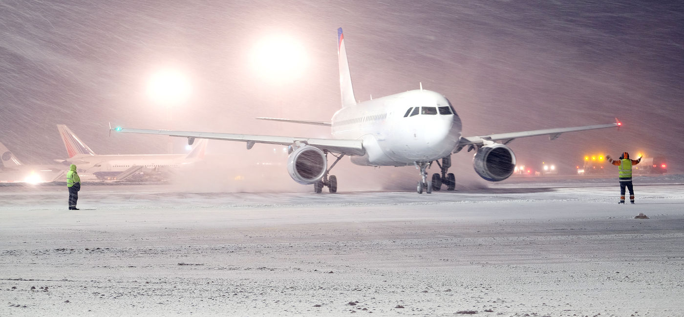 Image: Plane parked at the airport in winter snow. (photo via uatp2 / iStock / Getty Images Plus)